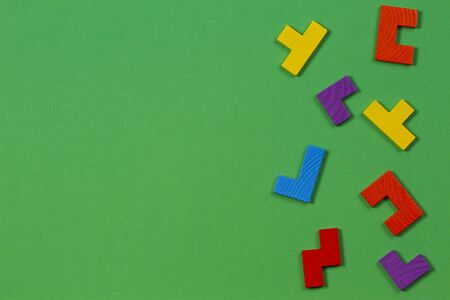 Different colorful shapes wooden blocks on green background. Top view
