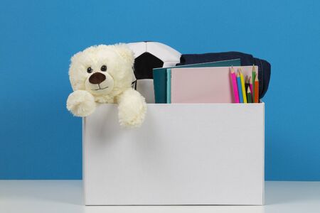 Donation box with toys, books, clothing for charity over blue backgroundの写真素材