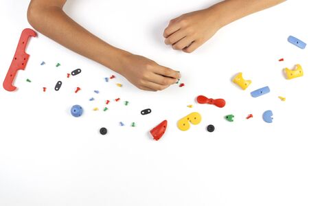 Kid hands playing with colorful plastic parts of constructor on white table. Top viewの写真素材