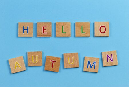 The words HELLO AUTUMN, spelt with wooden letter tiles over blue background. Top viewの写真素材