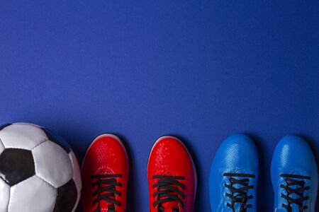Top view of soccer ball and two pairs of soccer football sports shoes on blue backgroundの写真素材