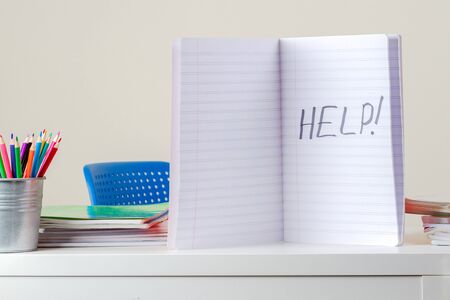 Help sign. Open notebook with written word Help on desk with pile books and notebooksの写真素材