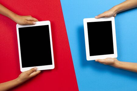 Kids holding tablet computer over red and light blue background