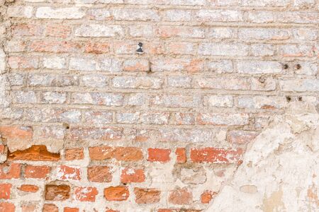 Grunge background. Red brick wall with bright abandoned plaster texture