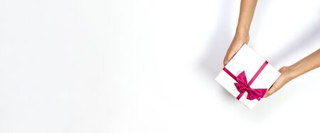 Child hands holding present gift box tied with ribbon on white background. Top view, place for text....
