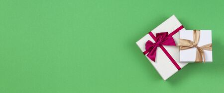 Two gift present boxes with ribbon on green background, top viewの写真素材