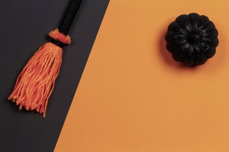 Halloween background. Decorative black shiny pumpkin on orange background and witch broom on black background. Top viewの写真素材