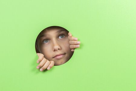 Kid watching through hole in green color background