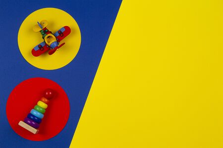 Baby kids toys background. Wooden stacking pyramid tower and red airplane on round yellow and red frames above navy blue backgroundの写真素材