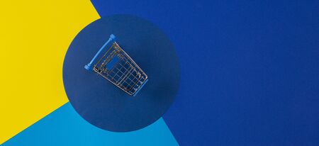 Mini shopping trolley cart on red yellow navy blue background. Online shopping, buy, sale, discount conceptの写真素材