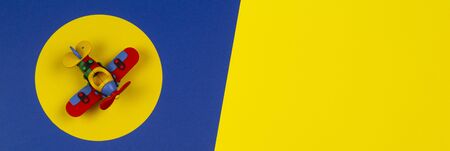 Baby kids toys banner background. Toy red airplane on round yellow frame above navy blue and yellow backgroundの写真素材