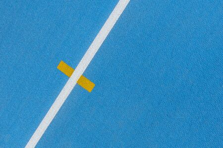 Sport background. Blue running track with white lines and yellow mark in sport stadium. Top view