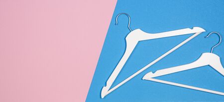 Two white wooden clothes hangers on pastel pink and light blue background. Shopping, sale, promo, social media, new season conceptの写真素材