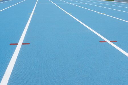 Blue running track with white lines and red mark in sport stadium. Top view