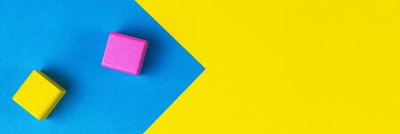 Wooden colorful blocks on geometric yellow and blue background. Top viewの写真素材
