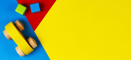 Wooden toy car with colorful blocks on geometric yellow blue green background. Top viewの写真素材