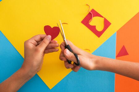 Paper crafts for kids. Child hands cutting colored paper with scissors at the table.の写真素材