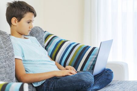 Preteen boy using laptop computer at home. Technology, online learning, distance education, home...