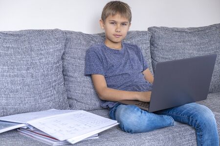Preteen boy doing homework mathematics tasks with laptop computer at home. Technology, online...