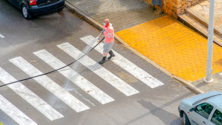 Villajoyosa, Spain - 09 April 2020: Sanitation worker washes and disinfects the street during Coronavirus pandemicのeditorial素材