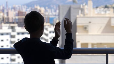 Applause to medical staff. Kid clapping hands, applauding from balcony to support doctors, nurses, hospital workers during Coronavirus pandemic quarantineの写真素材
