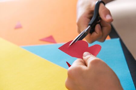 Paper crafts for kids. Child hands cutting colored paper with scissors at the tableの写真素材