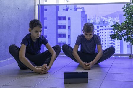 Children with tablet computer doing sport exercises, practicing yoga on balcony. Sport, healhty...
