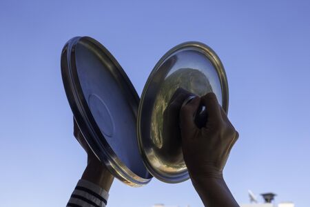 Woman hands banging pot lids against blue sky. Protest against the government measures. Banging pots...