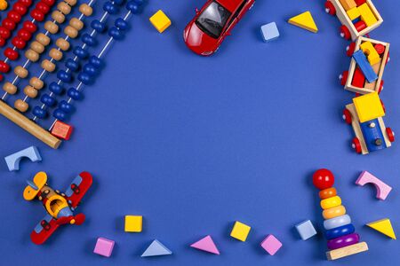 Kid toys background. Wooden educational geometric stacking blocks toy, wooden train, airplane and colorful blocks on navy blue background. Top view, flat layの写真素材