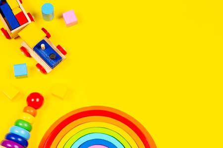 Baby kid toys background. Wooden toy train, wood rainbow and colorful blocks on yellow background. Top view, flat layの写真素材