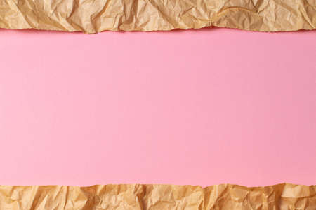 Torn crumpled recycled brown paper on light pink colored paper background insideの写真素材