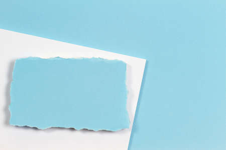 Blank white ripped piece of paper, torn paper card on white and light blue background. Top viewの写真素材
