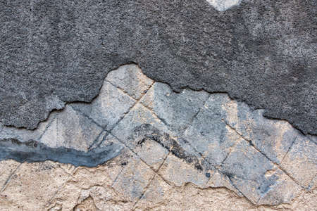 Old decrepit dirty plaster wall background with cracked structure. Old black gray grey mortar wall...
