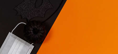 Black halloween eye mask, little black pumpkin and medical protective face mask on orange backgroundの写真素材