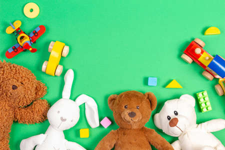 Baby kids toys background. Teddy bears, wooden train, toy cars, colorful blocks on light green background. Top viewの写真素材