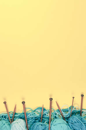 Brown wooden knitting needles and knitting wool on yellow background. Top viewの写真素材