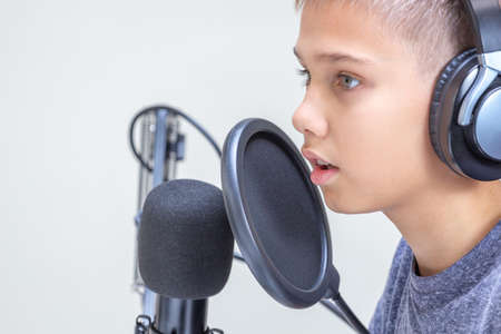 Portrait of teenage boy wearing headphones using microphone. Online learning, remote education, video game, podcast conceptの写真素材