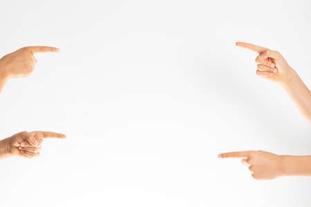 Many hands pointing with index fingers on white wall background