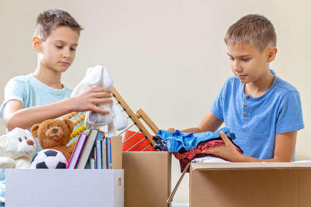 Kids volunteers sorting toys, clothes, books, donation goods in donate charity boxesの写真素材
