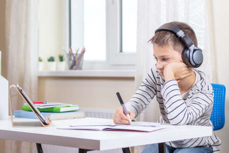 Online learning, remote education at home. Kid with digital tablet computer having online leasson, making homeworkの写真素材