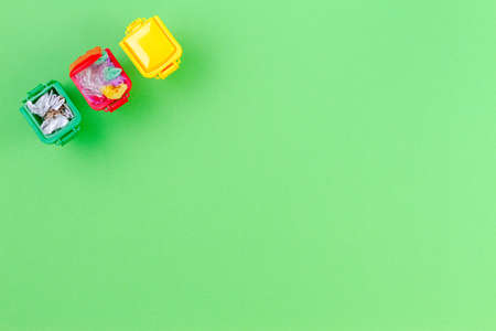 Colorful recycle bins container with garbage on green background