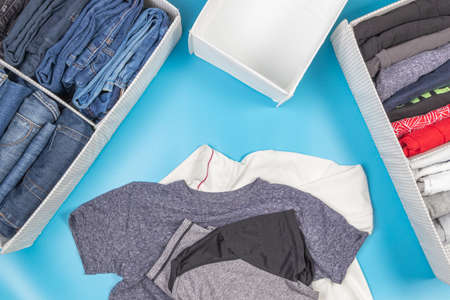 Vertical storage of clothing, tidying up, room cleaning concept. Stack of folded t shirt and jeans...