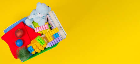 Christmas donation box with baby kid toys, books, clothing for charity on yellow background. Top viewの写真素材