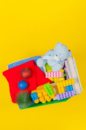 Christmas donation box with baby kid toys, books, clothing for charity on yellow background. Top viewの写真素材