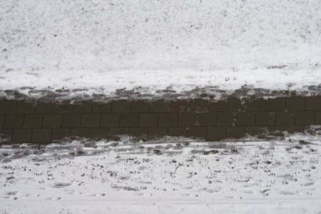 Maintenance of streets and sidewalks in winter. Snowy cleaned sidewalk and human footprints on pedestrian path. Aerial viewの写真素材