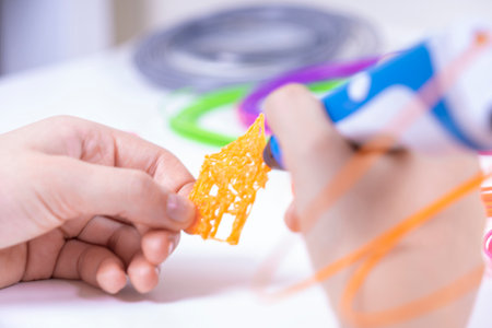 Child hands creating new 3d object with 3d pen. Learning and entertainment at home. Top view