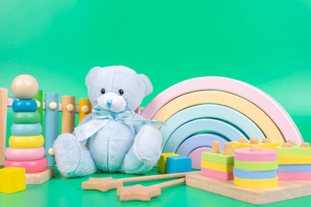 Kids toys collection. Teddy bear, wooden rainbow, educational and music baby toys on light green backgroundの写真素材