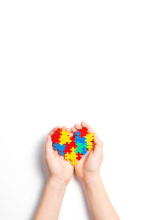 Child hands holding colorful heart on white background. World autism awareness day conceptの写真素材