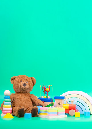 Kids toys collection. Teddy bear, wooden rainbow, train and baby toys on light green backgroundの写真素材