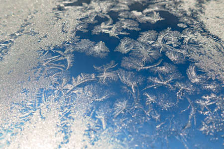 Frozen surface with icy pattern on window glass in cold winter day